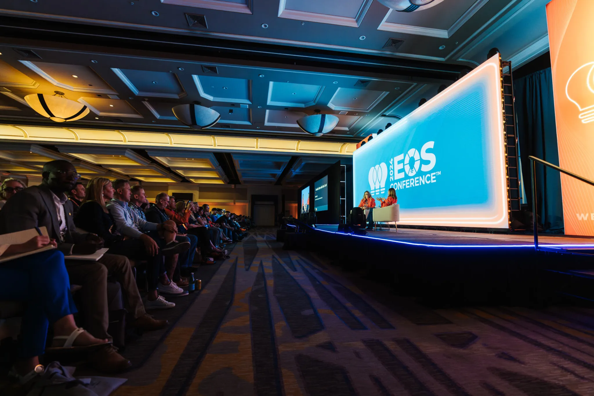 Audience watching a speaker on the EOS Conference main stage with a large LED wall reading ‘EOS Conference’