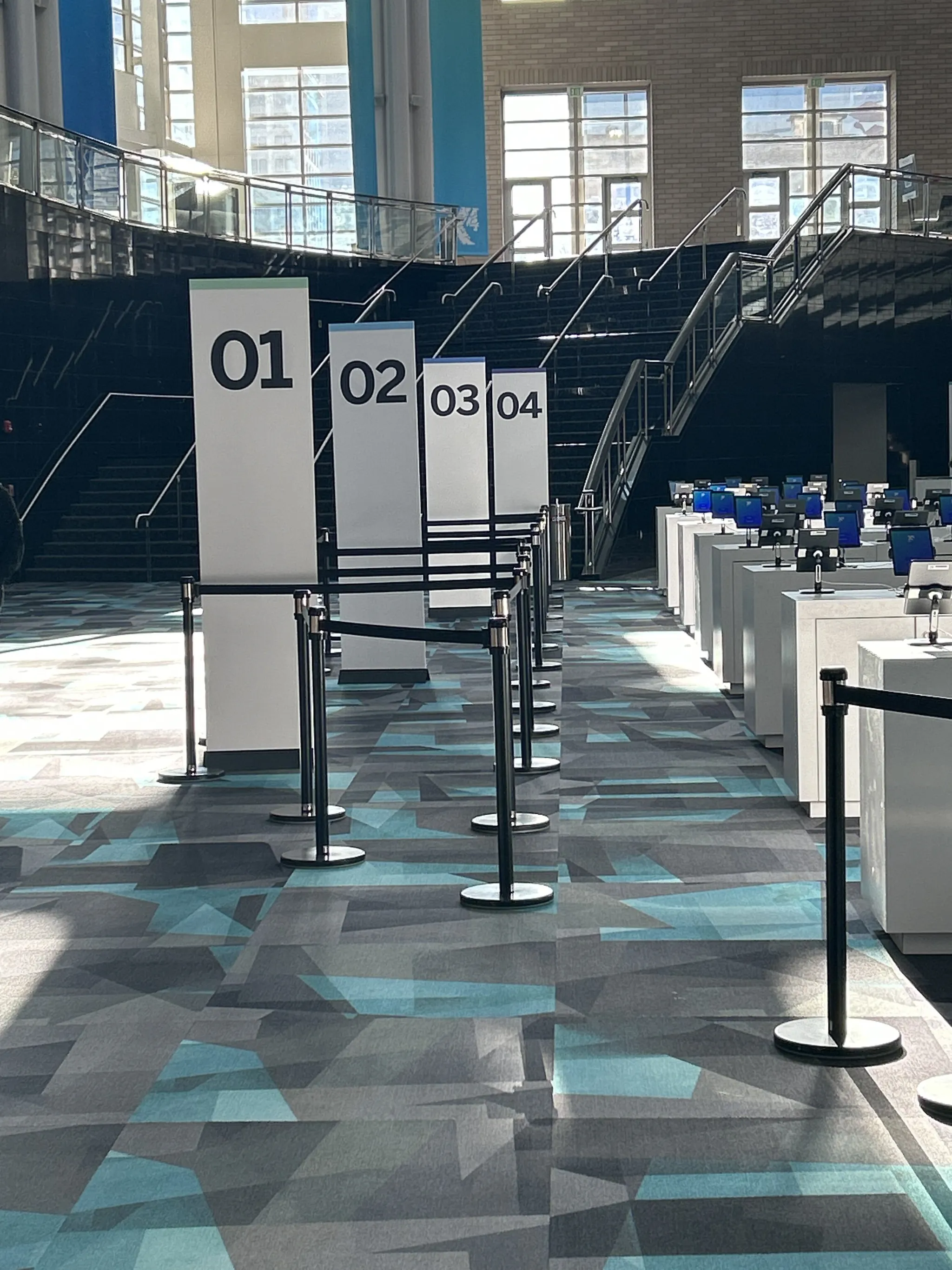 Zero-line registration kiosks numbered 01 through 04 lined up in the X4 Summit convention atrium