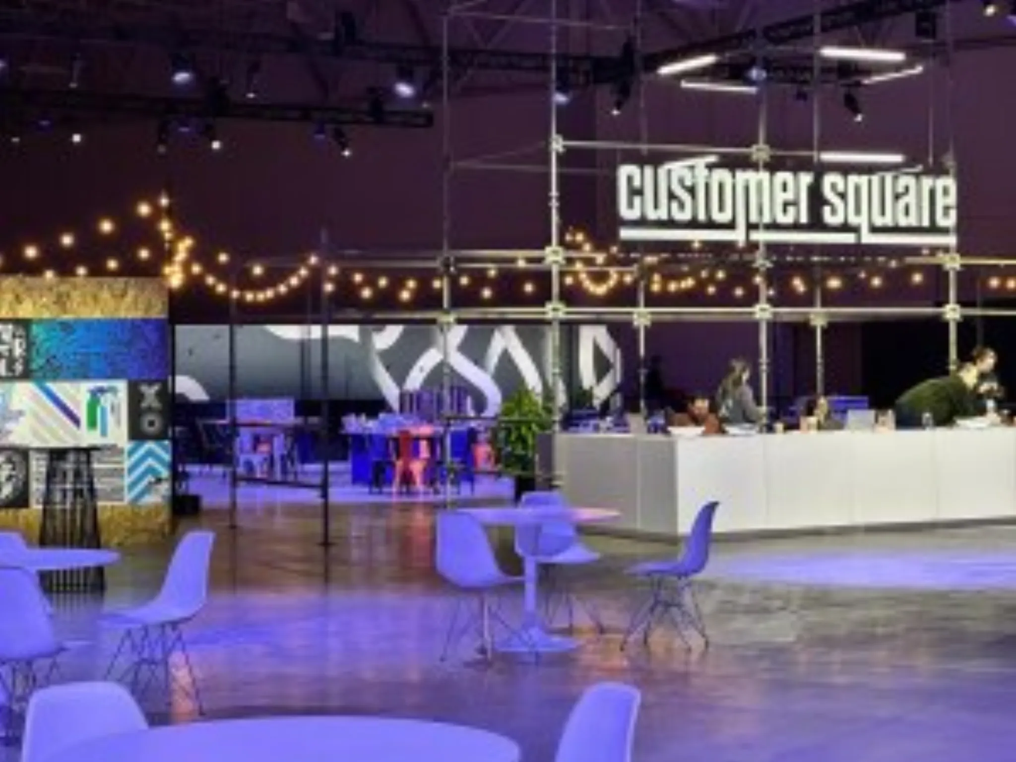 Qualtrics X4 Customer Square sponsor expo activation with white lounge seating and branded lighting