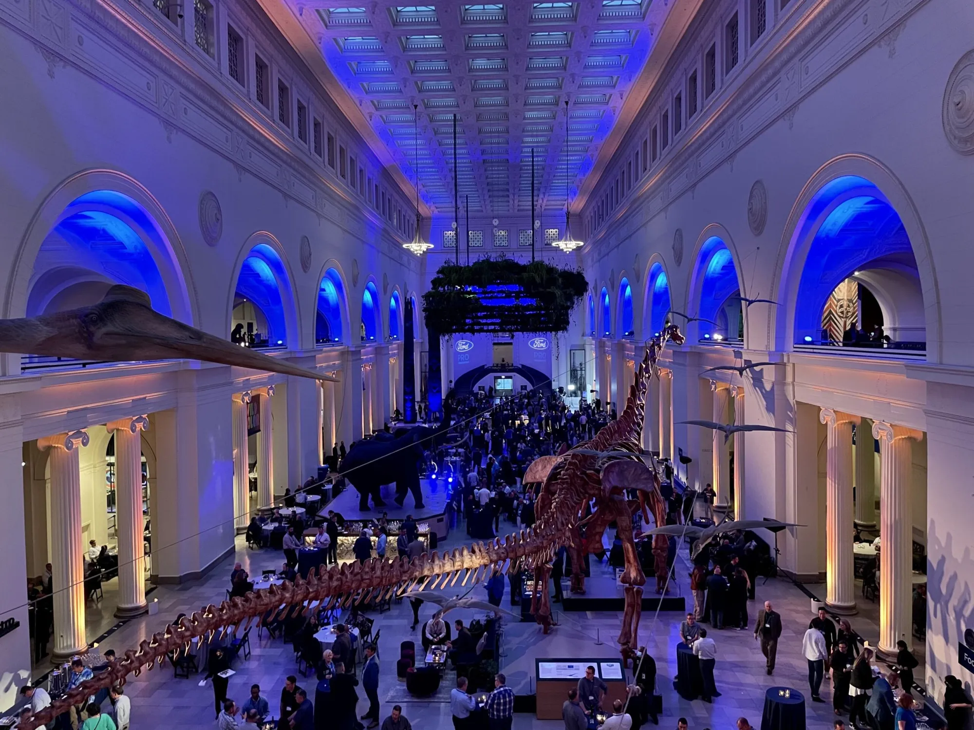 Field Museum great hall with dinosaur skeleton, blue lighting and Ford Pro signage