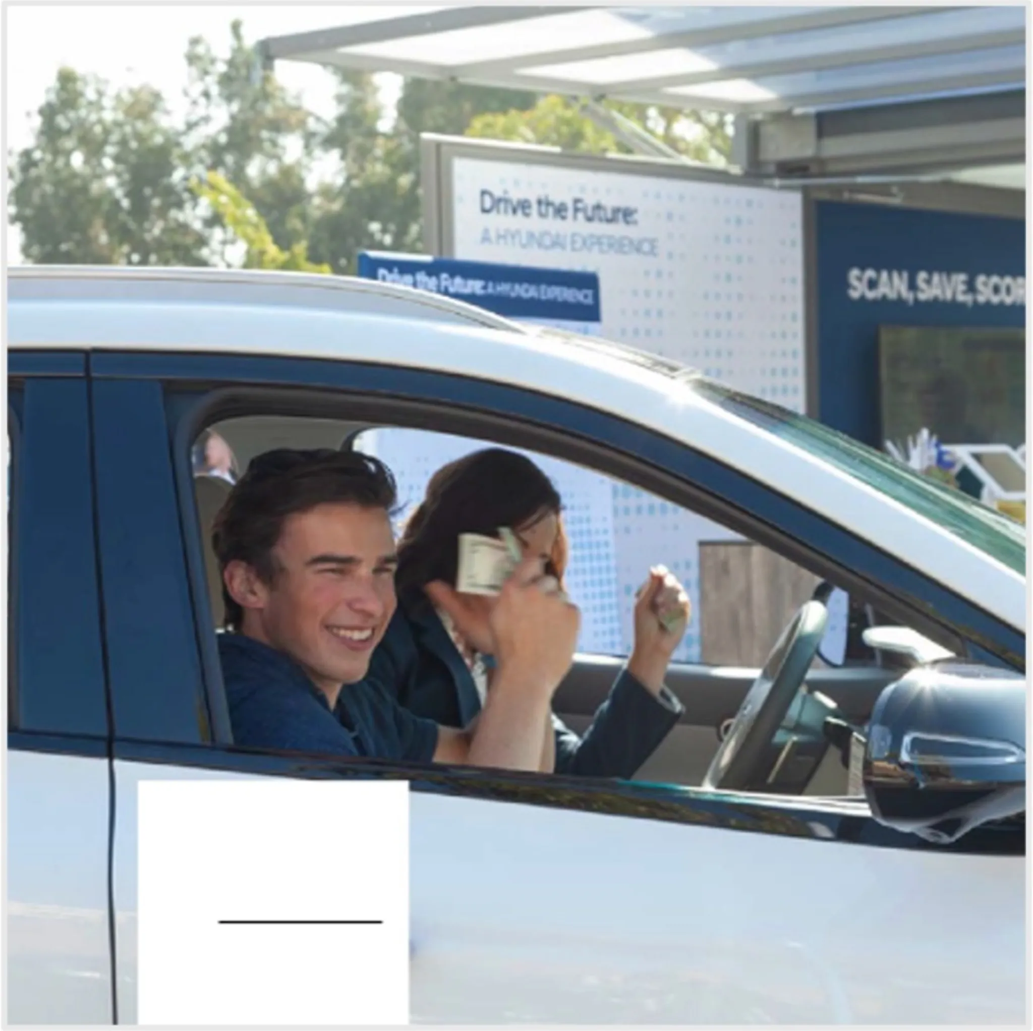 Two students smiling inside a Hyundai electric vehicle at the Drive the Future campus activation