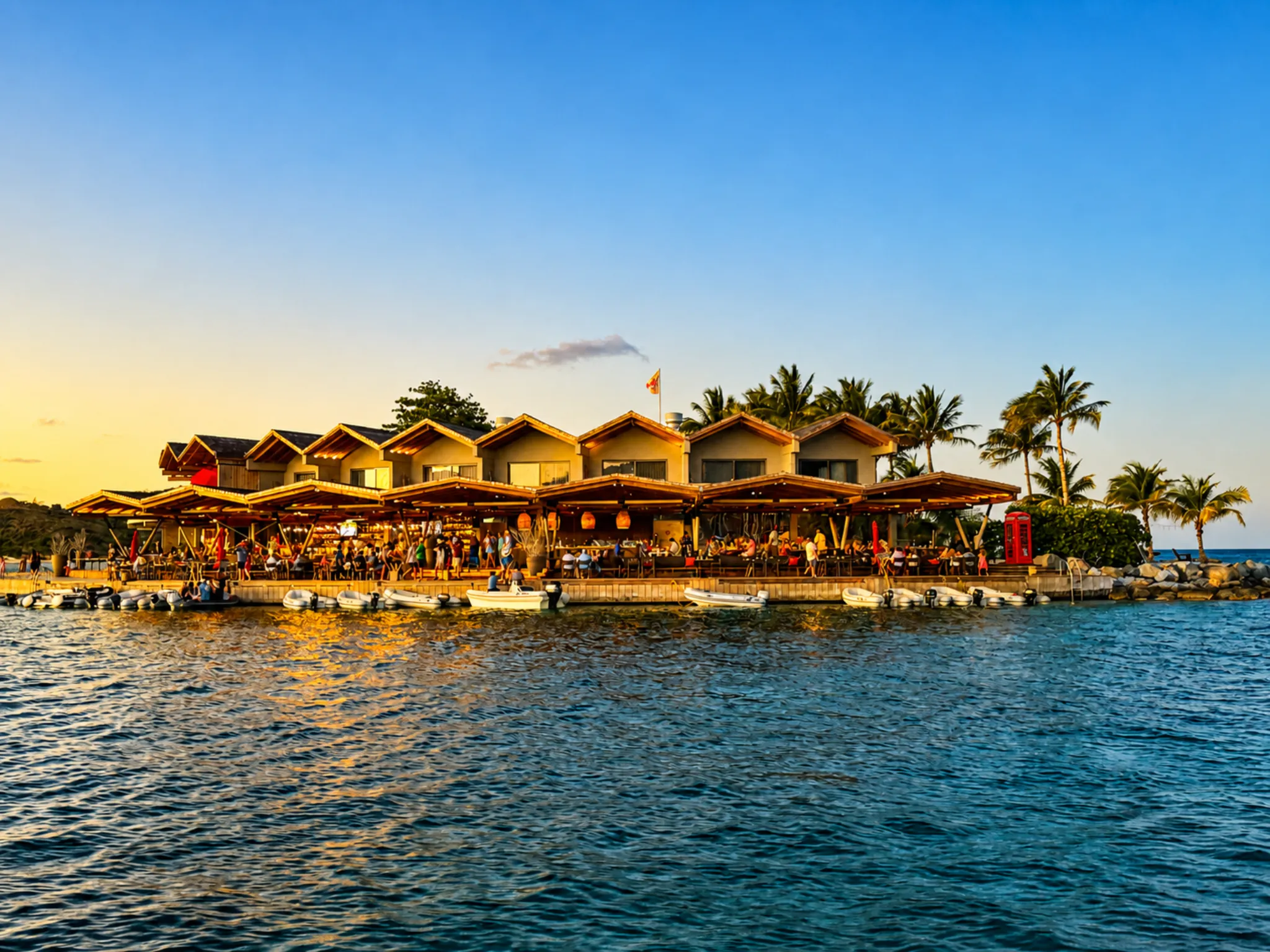 Waterfront restaurant village glowing at sunset along a calm Caribbean dock